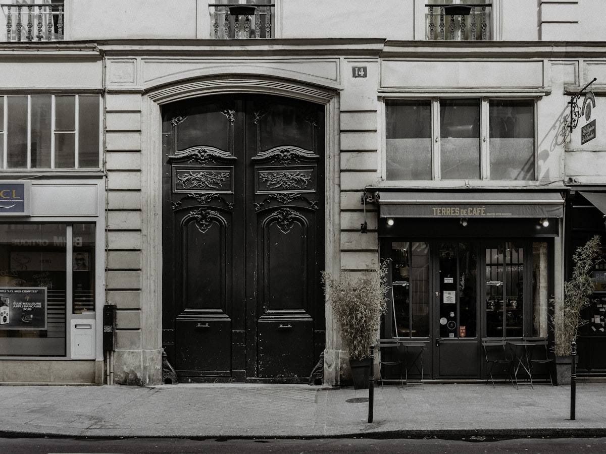 Porte cochère et devanture sur une façade d'immeuble ancien.