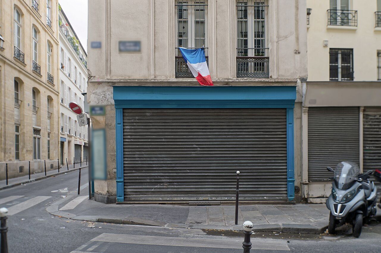 Boutique d'angle, rideau métallique baissé dans un encadrement bleu.