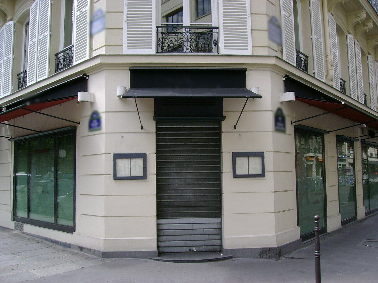 Restaurant à l'angle d'un immeuble haussmannien, rideau métallique baissé.