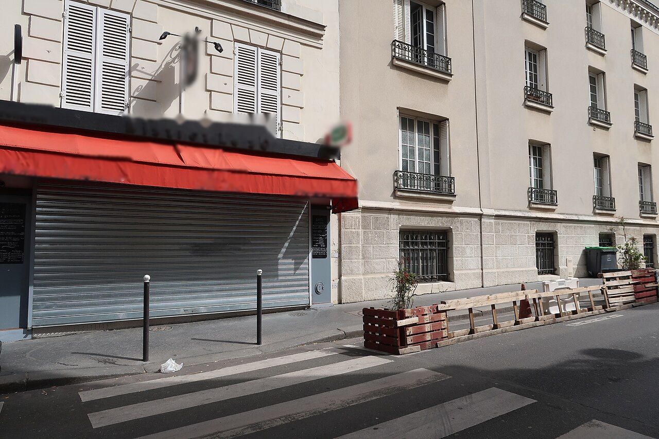 Bistrot sous un store rouge, rideau métallique baissé sur toute la largeur.